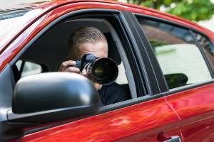private investigator sitting in car taking pictures