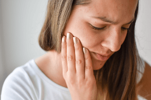 woman rubbing jaw in pain