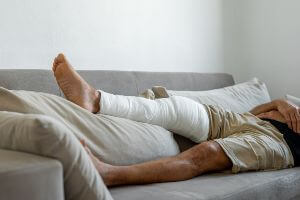 man with bandaged leg on couch