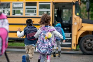 school children running to yellow school bus