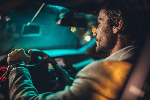 bearded young male driver in car at night