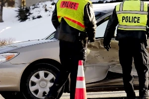 two police officers approaching a vehicle that has had a winter side impact collision