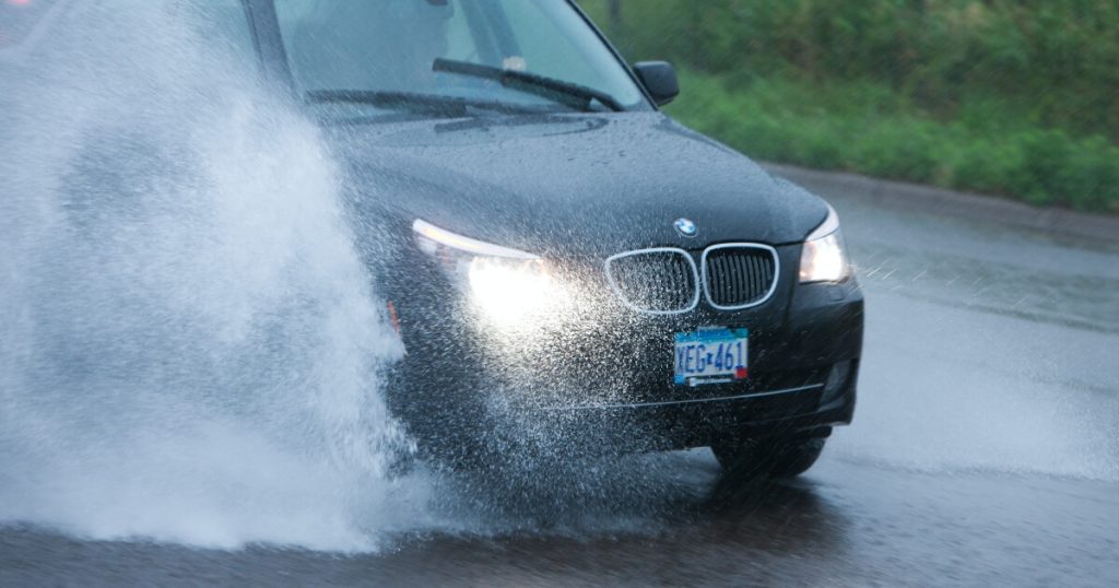 Current image: A car riding fast through a puddle creating a wave