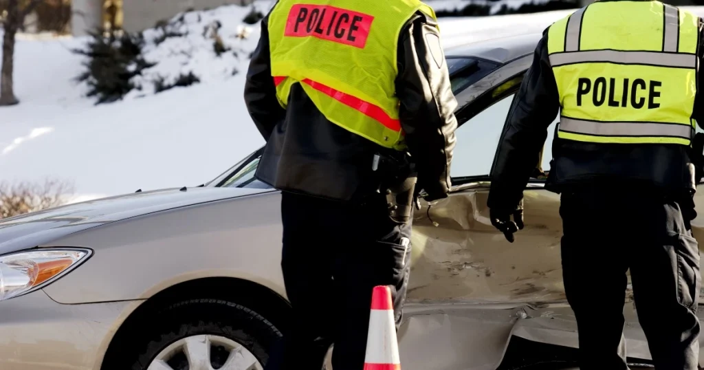 Current image: two police officers approaching a vehicle that has had a winter side impact collision