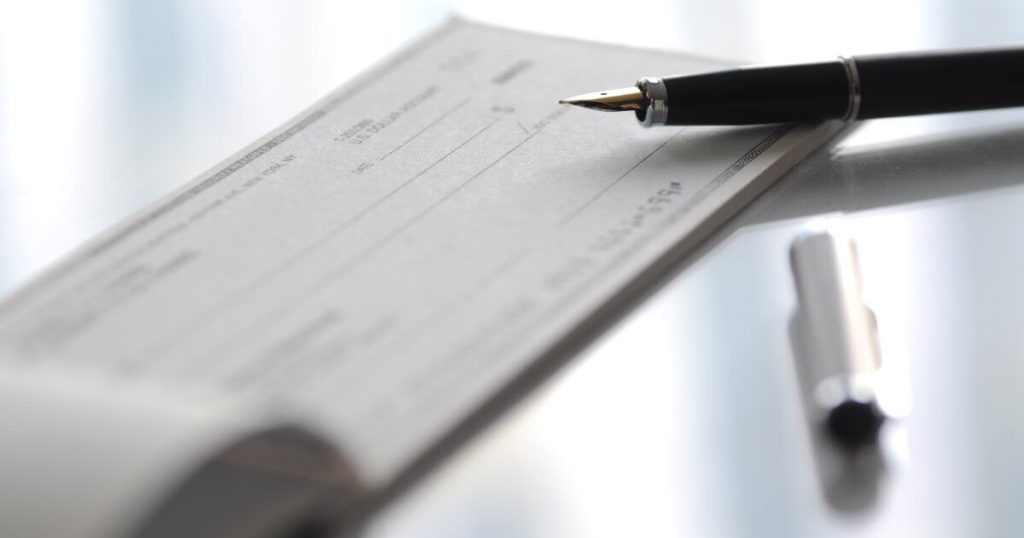 Current image: checkbook on table with pen