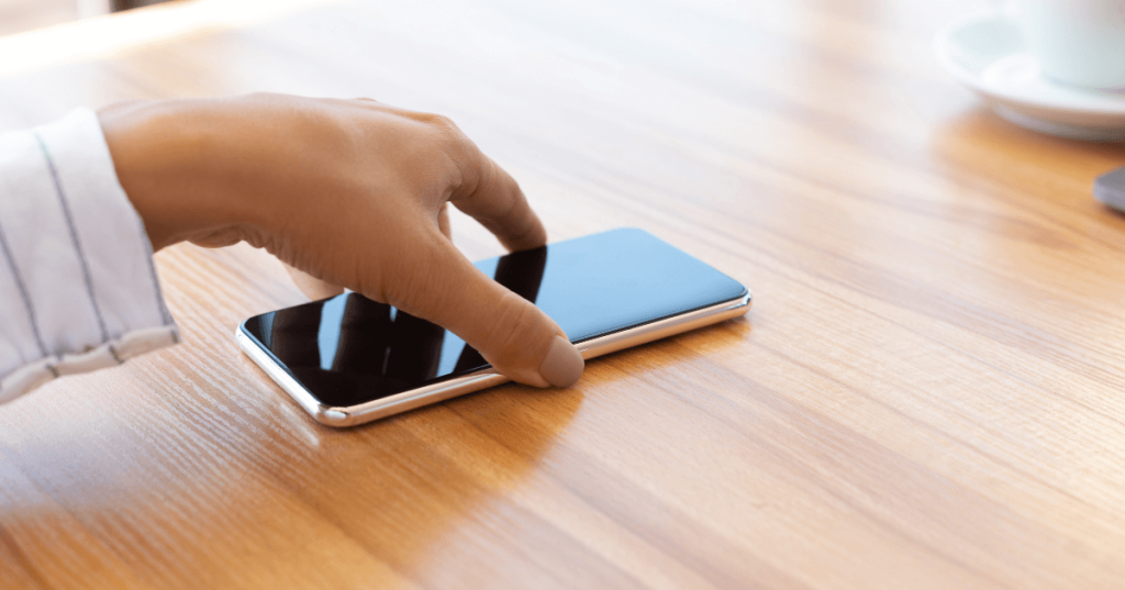 Current image: grabbing smartphone from table social|reaching for smartphone on table