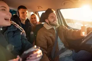 car full of teenaged drivers in winter coats, buckled up and looking happy