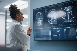 doctor standing before a screen showing the MRI of a brain injury
