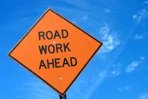 "Road Work Ahead" sign against blue sky