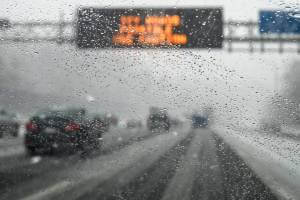 snowy road with digital sign over road