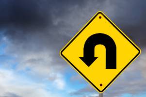 yellow u-turn sign in front of cloudy sky