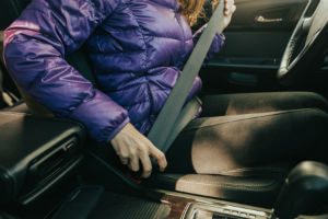 woman in winter coat using seat belt