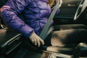 woman in winter coat using seat belt