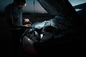 working on car engine at dusk on roadside