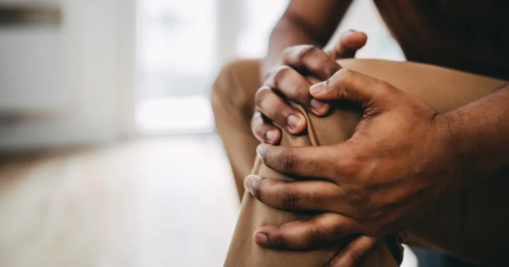 Current image: Close up of young black man's holding injured knee. You do not see the man's face.|Close up of young black man's holding injured knee. You do not see the man's face.