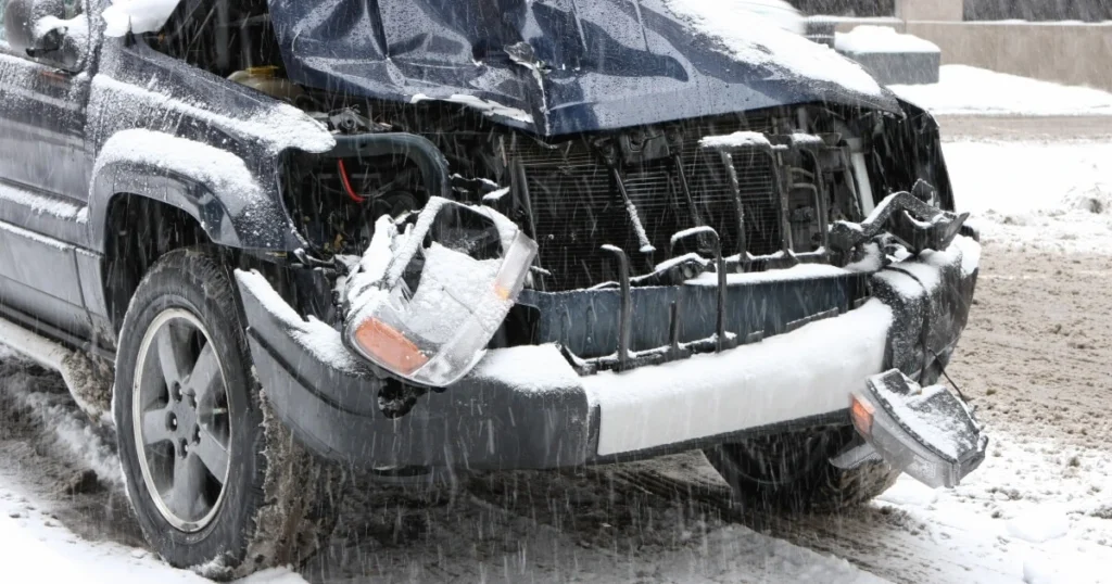 Current image: image shows smashed-in front end of a black SUV in snow