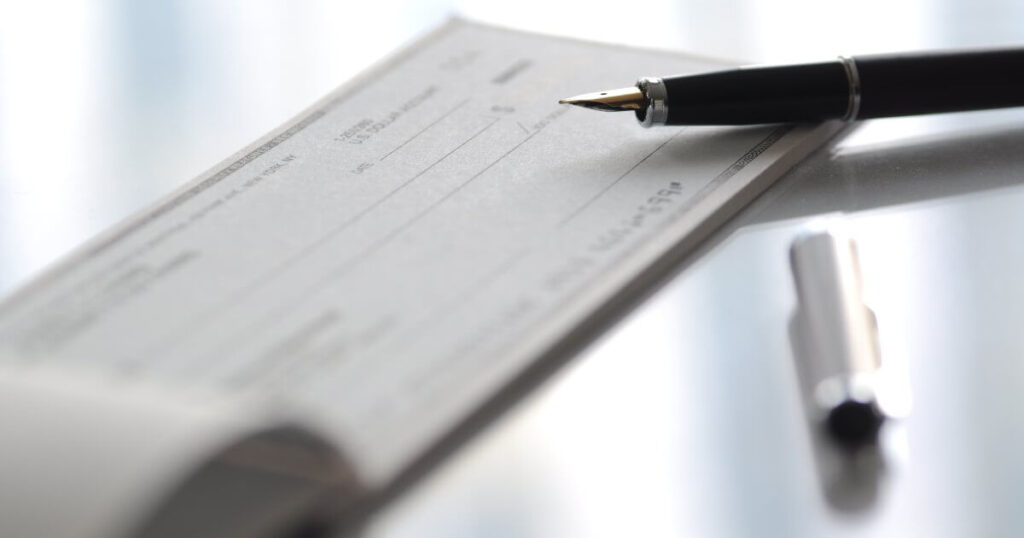Current image: checkbook on table with pen