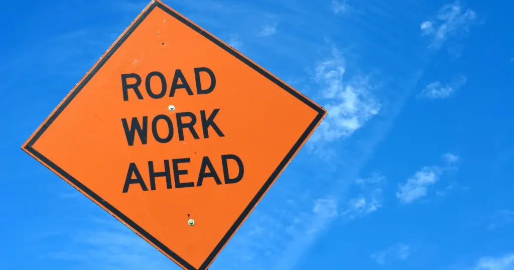 Current image: "Road Work Ahead" sign against blue sky