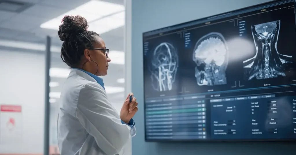 Current image: doctor standing before a screen showing the MRI of a brain injury